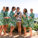 bridesmaids toast in robes by ocean